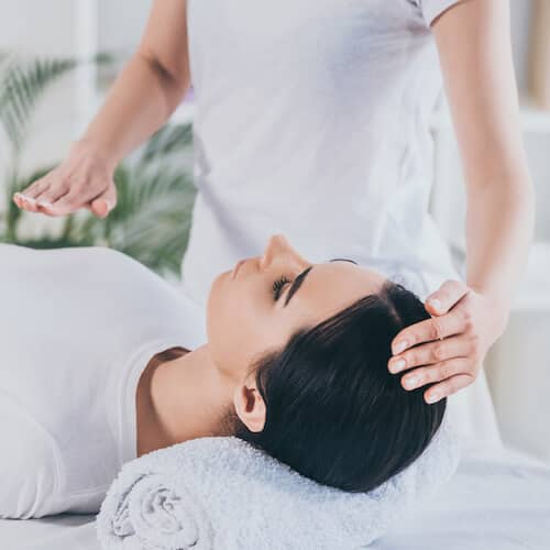 A woman laying peacefully on a massage table receiving a Reiki Bunbury energy healing therapy